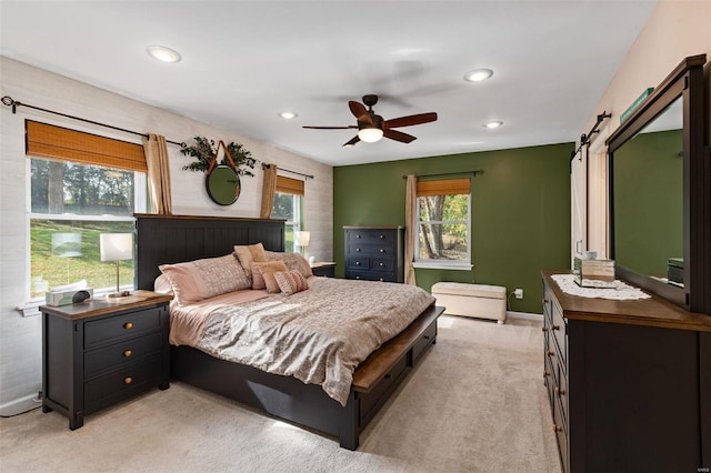 bedroom featuring a barn door, light colored carpet, and ceiling fan