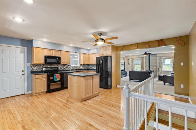 kitchen with decorative backsplash, a kitchen island, sink, black appliances, and light wood-type flooring