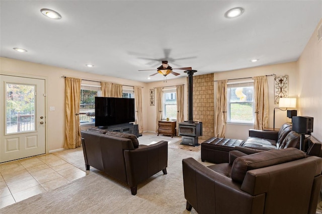 living room featuring light tile patterned flooring, a wood stove, and ceiling fan