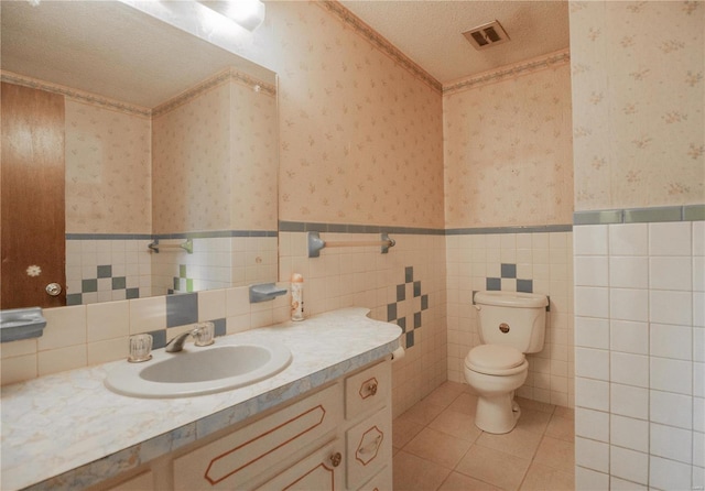 bathroom featuring vanity, a textured ceiling, tile walls, and toilet