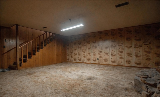 basement with a textured ceiling, carpet, and wooden walls