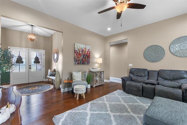 living room with french doors, ceiling fan with notable chandelier, and dark wood-type flooring