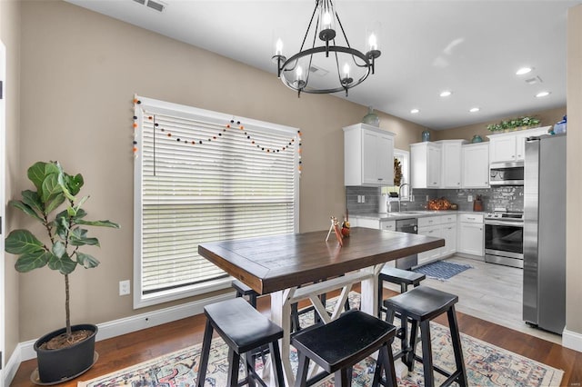 dining room with a notable chandelier, light hardwood / wood-style flooring, and sink