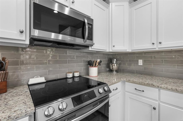 kitchen featuring decorative backsplash, stainless steel appliances, white cabinetry, and light stone countertops