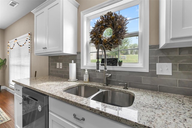 kitchen with light stone countertops, white cabinets, wood-type flooring, and stainless steel dishwasher