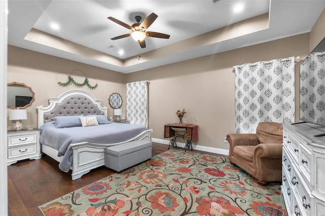 bedroom with ceiling fan, a raised ceiling, and hardwood / wood-style floors