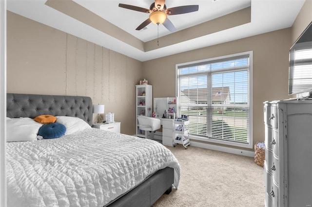 bedroom featuring ceiling fan, a raised ceiling, and light carpet