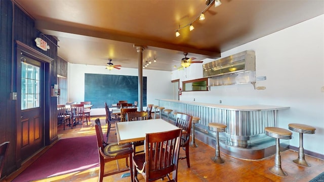 dining space featuring ceiling fan, bar area, and beam ceiling