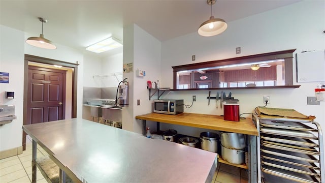 kitchen with decorative light fixtures, light tile patterned floors, and ceiling fan