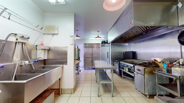 kitchen with light tile patterned floors, stainless steel refrigerator, and range hood