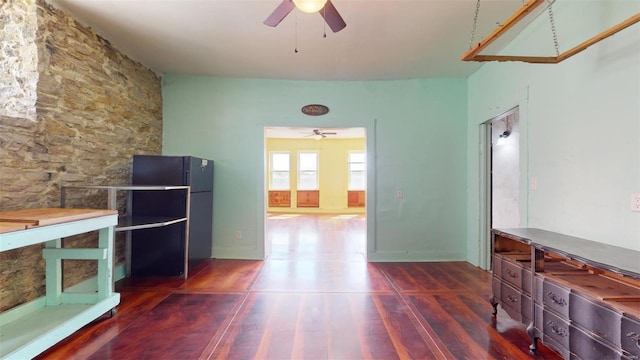 unfurnished living room featuring dark wood-type flooring and ceiling fan