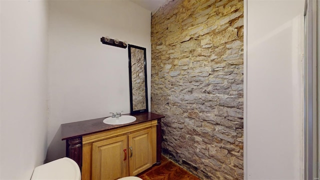 bathroom with parquet floors, vanity, and toilet