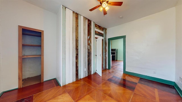 interior space with ceiling fan and dark parquet flooring