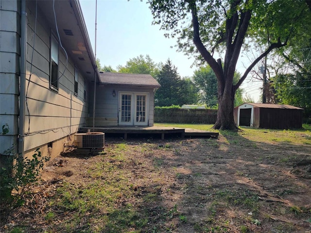 view of yard with a storage unit, a deck, central air condition unit, and french doors