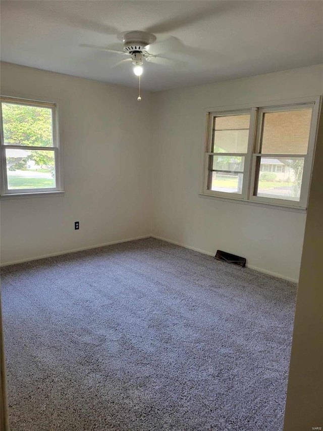 empty room with ceiling fan, plenty of natural light, and carpet flooring