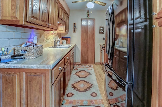 kitchen with ceiling fan, sink, light hardwood / wood-style flooring, backsplash, and black refrigerator