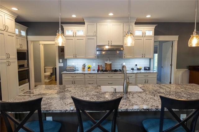 kitchen featuring a breakfast bar, stainless steel appliances, sink, and pendant lighting