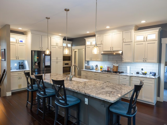 kitchen featuring stainless steel appliances, sink, an island with sink, and hanging light fixtures