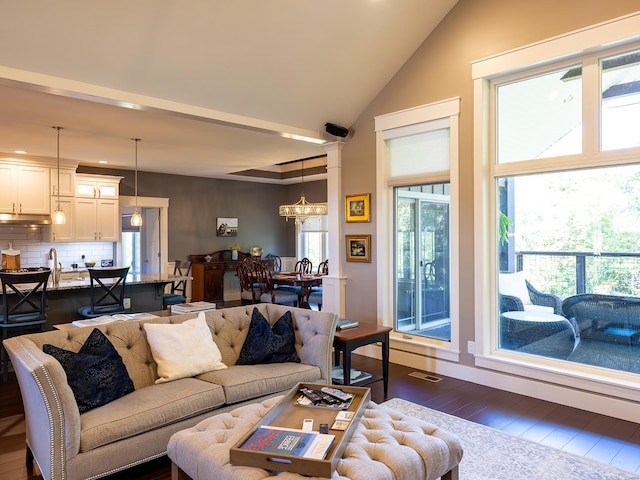 living room featuring a wealth of natural light, dark wood-type flooring, and an inviting chandelier