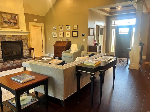 living room featuring vaulted ceiling, a stone fireplace, and dark hardwood / wood-style floors