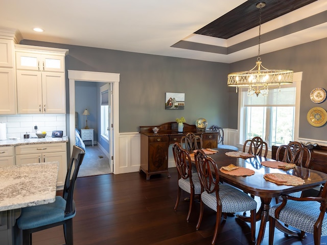 dining room featuring a tray ceiling, dark hardwood / wood-style flooring, and an inviting chandelier