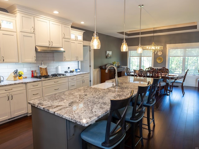 kitchen featuring a large island, stainless steel gas cooktop, dark hardwood / wood-style flooring, and pendant lighting