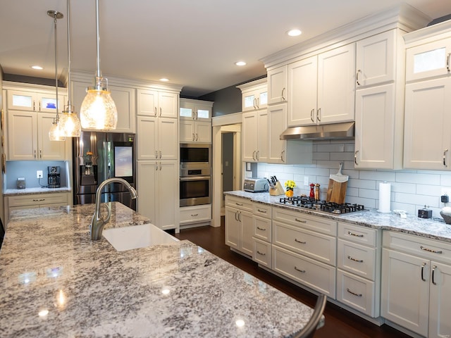 kitchen featuring light stone countertops, sink, appliances with stainless steel finishes, and pendant lighting