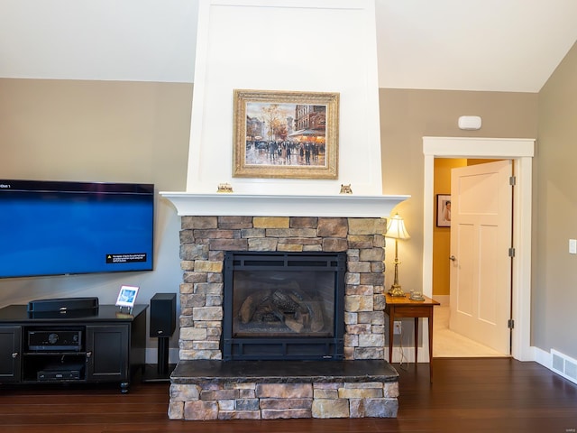 living room with a stone fireplace and dark hardwood / wood-style flooring