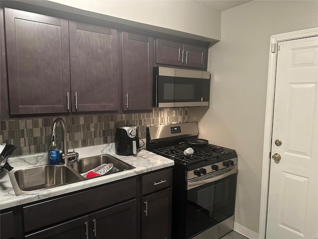 kitchen with appliances with stainless steel finishes, decorative backsplash, dark brown cabinetry, and sink