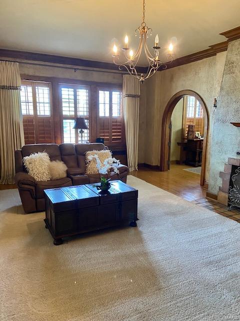 living room with wood-type flooring, an inviting chandelier, and ornamental molding