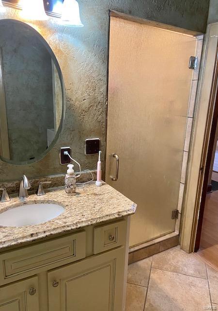 bathroom with tile patterned floors, a shower with shower door, and vanity