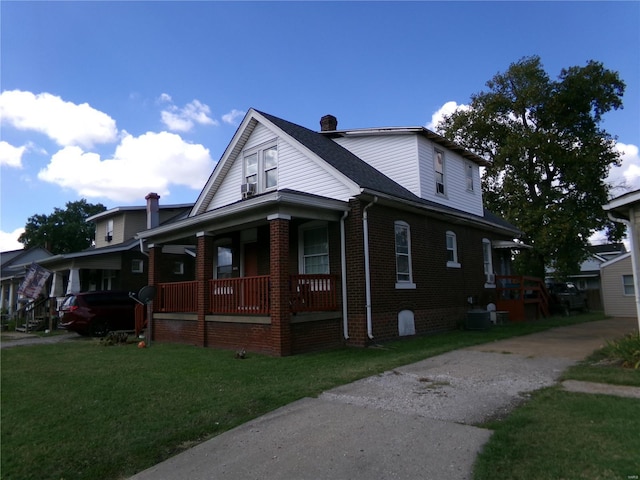 view of property exterior featuring covered porch, a chimney, central AC unit, brick siding, and a yard