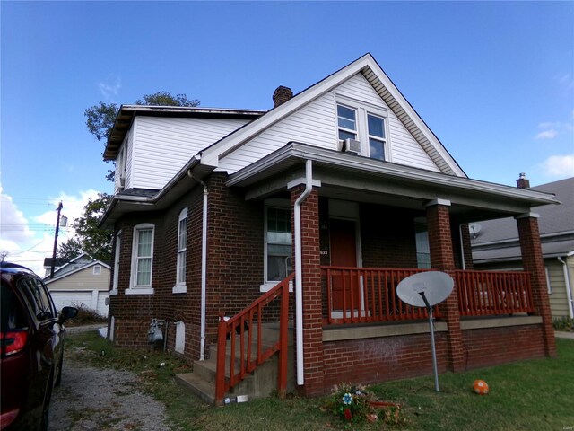 bungalow-style home with brick siding, cooling unit, and a porch