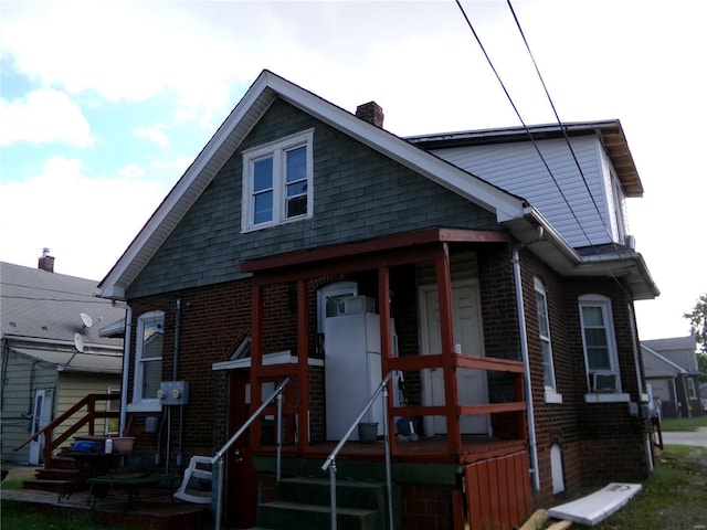 bungalow-style house with a chimney and brick siding