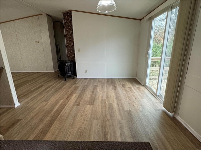 unfurnished living room with hardwood / wood-style flooring, a wood stove, and ornamental molding