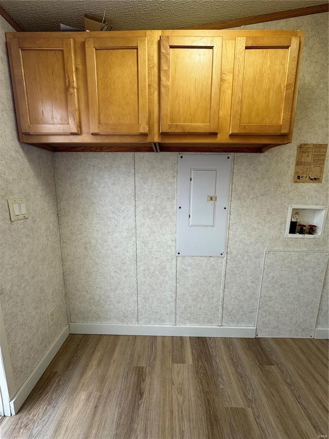 clothes washing area featuring hardwood / wood-style floors, cabinets, electric panel, and washer hookup