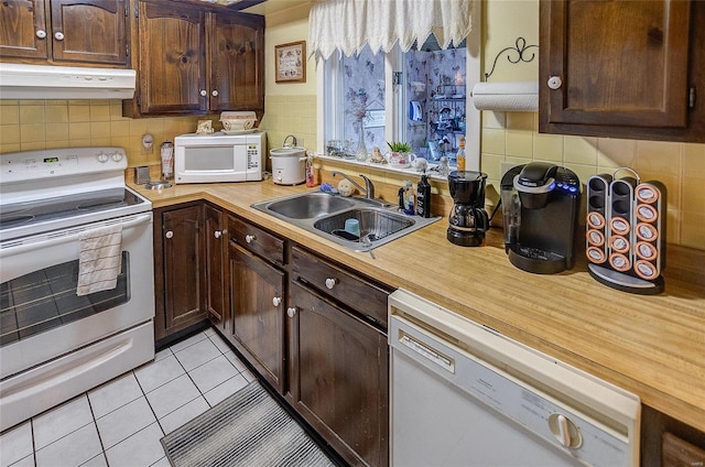 kitchen featuring dark brown cabinets, white appliances, sink, and light tile patterned floors