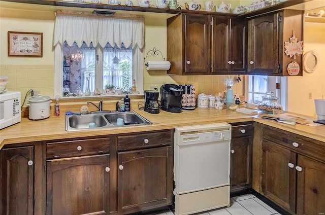 kitchen with white appliances, dark brown cabinets, sink, and plenty of natural light