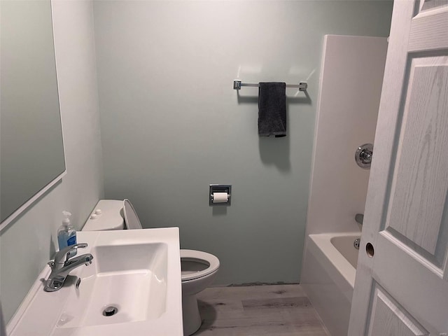 full bathroom featuring wood-type flooring, bathing tub / shower combination, sink, and toilet