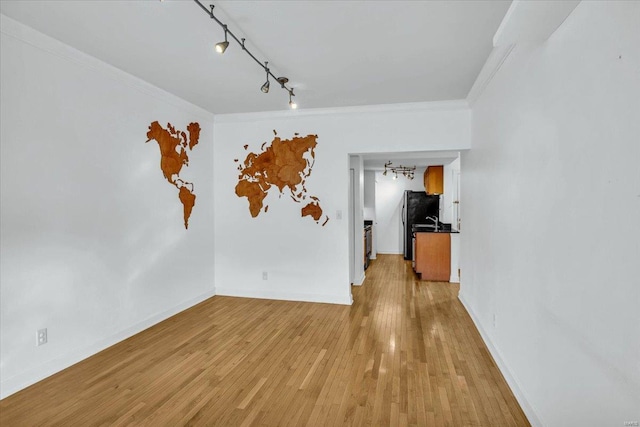 spare room with crown molding, rail lighting, and light hardwood / wood-style floors