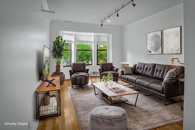 living room with track lighting, ornamental molding, and hardwood / wood-style floors