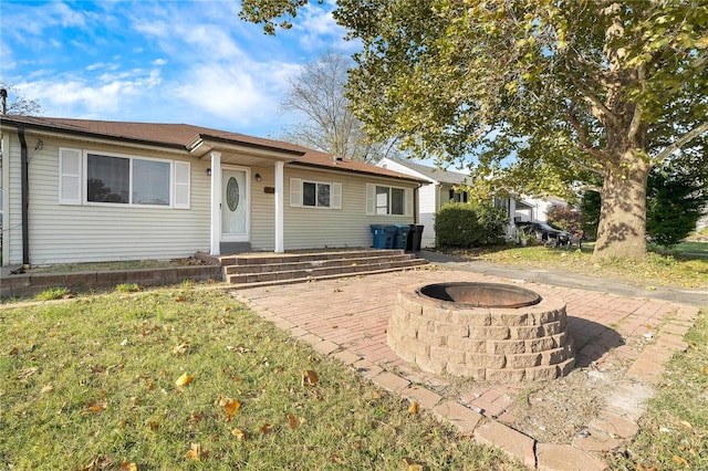 ranch-style house with an outdoor fire pit, a patio area, and a front yard