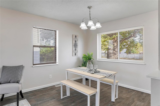 dining space featuring a textured ceiling, dark hardwood / wood-style flooring, and an inviting chandelier