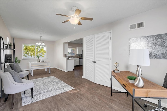 interior space featuring dark wood-type flooring and ceiling fan with notable chandelier