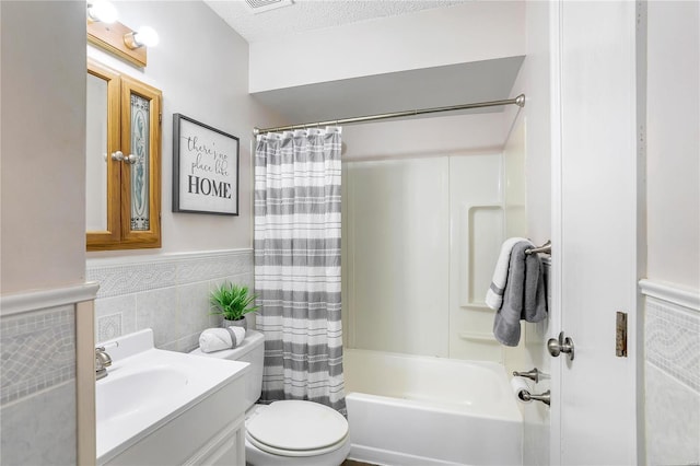 full bathroom with shower / bath combination with curtain, a textured ceiling, tile walls, toilet, and vanity