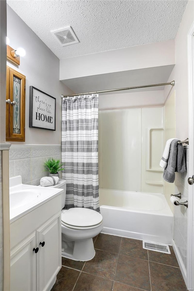 full bathroom featuring toilet, vanity, shower / tub combo with curtain, tile walls, and a textured ceiling