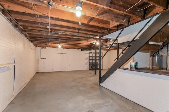 basement featuring water heater and brick wall