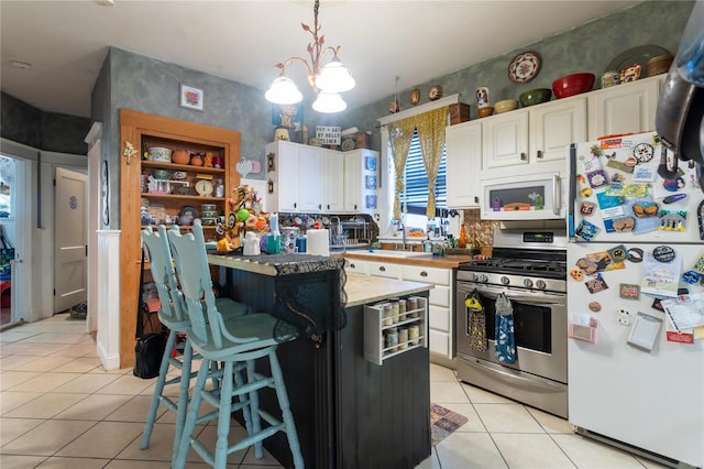 kitchen with pendant lighting, white appliances, white cabinetry, and light tile patterned floors