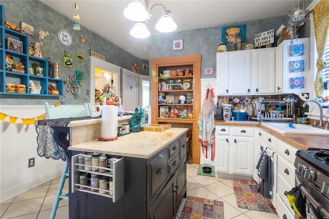 kitchen featuring gas range, hanging light fixtures, white cabinetry, and light tile patterned floors