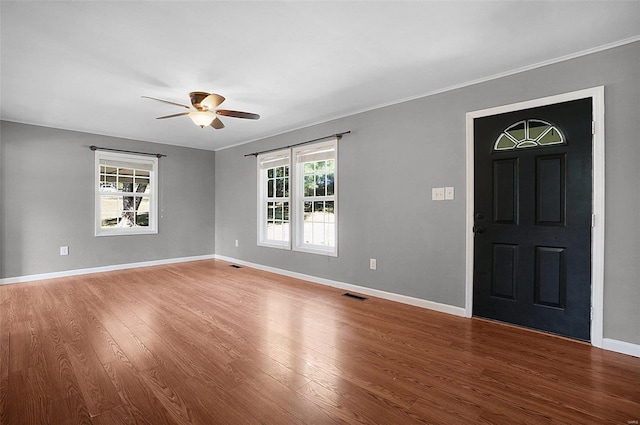 foyer entrance with ornamental molding, wood-type flooring, ceiling fan, and a healthy amount of sunlight